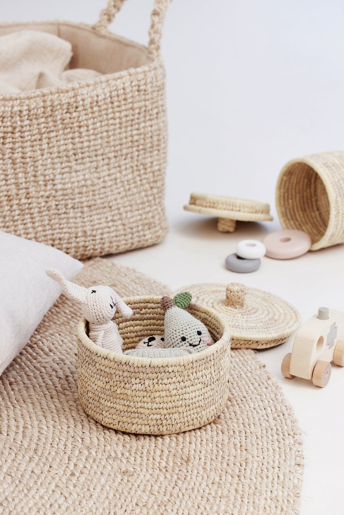 small palm leaf basket with children&#39;s toys on jute rug